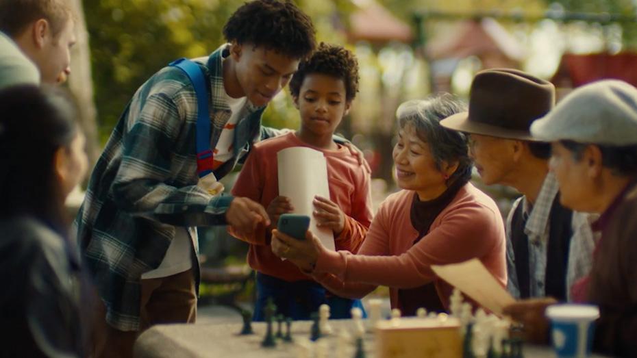 A group of smiling people gather around a phone.