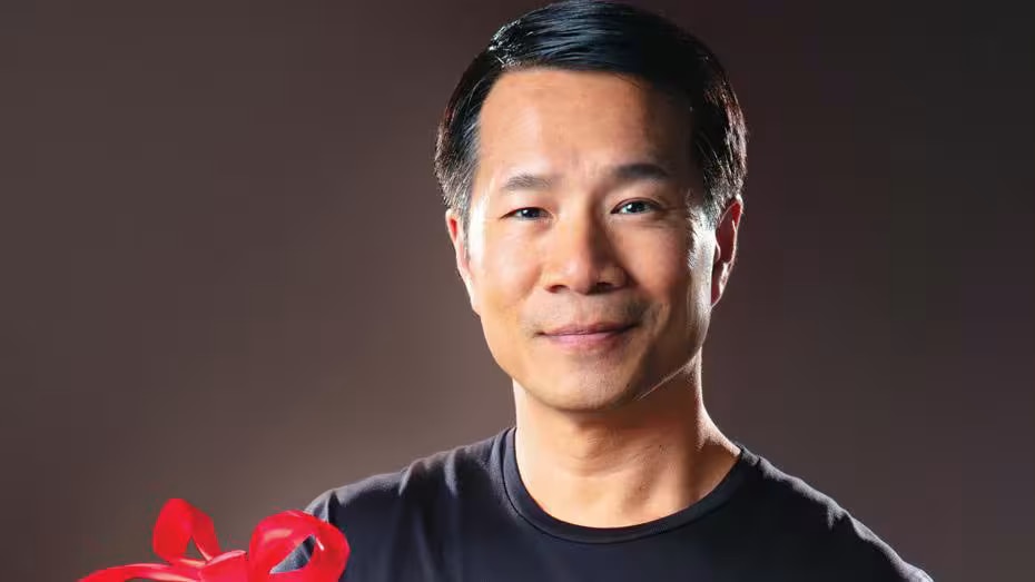 A man is looking into the camera and smiling while holding a gift.