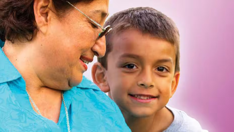 A woman and child are sitting with each other and smiling.