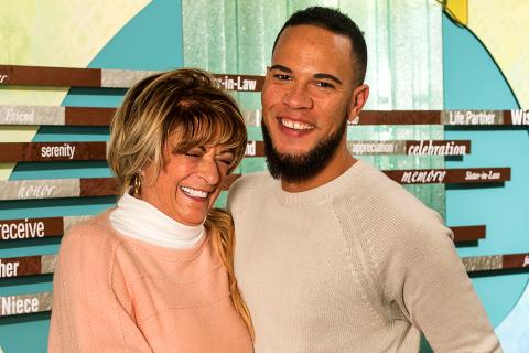 Ryan, standing next to his smiling mother, smiles at the camera.