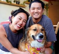 Angel smiles at the camera next to a dog and a smiling man.