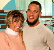 Ryan, de pie junto a su madre sonriente, sonríe a la cámara.​​​​​​​